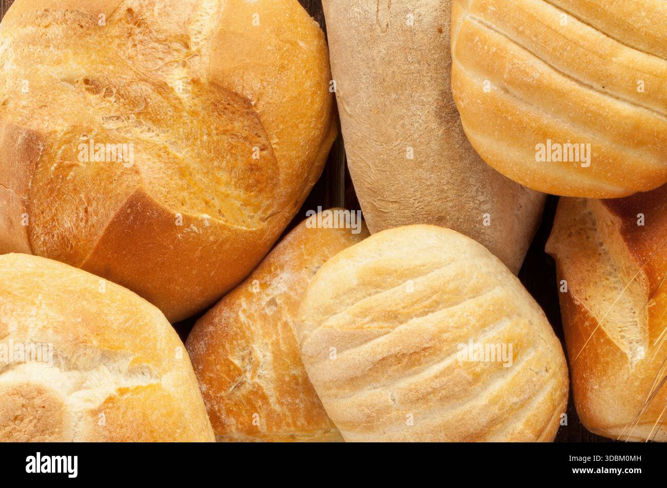 Frisch gebackene Brotlaibe, die in einem Korb gekühlt werden und verschiedene Texturen und Krusten zeigen Stockfoto