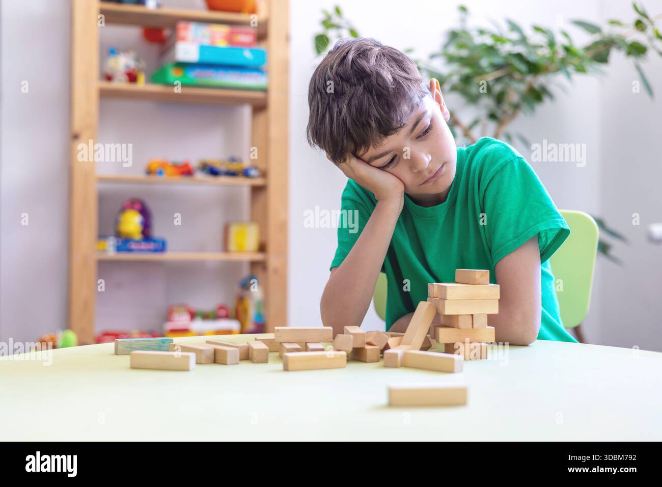 Kind zeigt Frustration während der Lernaktivität mit Holzblöcken. Schwierigkeiten mit der Aufgabenpersistenz bei Kindern mit Autismus oder Dyspraxie. Stockfoto