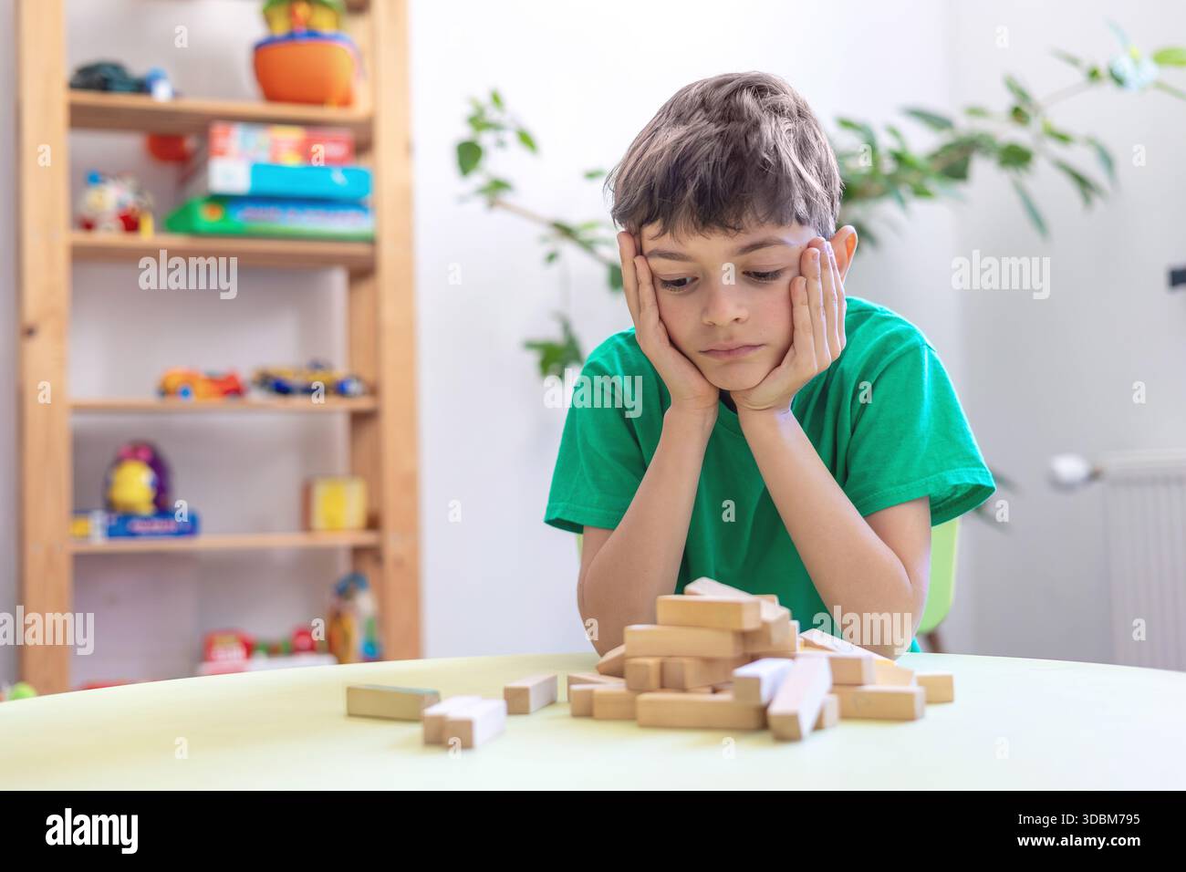 Kind zeigt Frustration während der Lernaktivität mit Holzblöcken. Schwierigkeiten mit der Aufgabenpersistenz bei Kindern mit Autismus oder Dyspraxie. Stockfoto