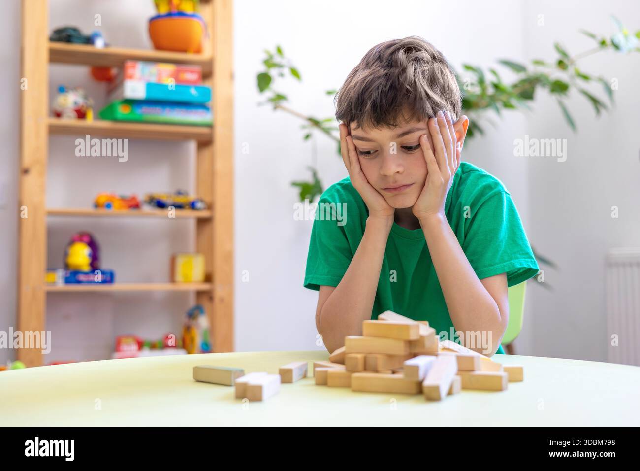 Kind zeigt Frustration während der Lernaktivität mit Holzblöcken. Schwierigkeiten mit der Aufgabenpersistenz bei Kindern mit Autismus oder Dyspraxie. Stockfoto