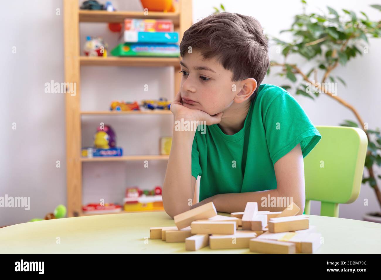 Kind zeigt Frustration während der Lernaktivität mit Holzblöcken. Schwierigkeiten mit der Aufgabenpersistenz bei Kindern mit Autismus oder Dyspraxie. Stockfoto