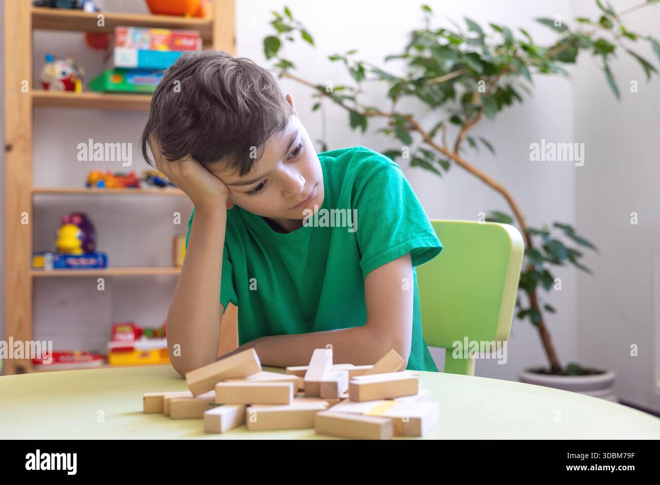 Kind zeigt Frustration während der Lernaktivität mit Holzblöcken. Schwierigkeiten mit der Aufgabenpersistenz bei Kindern mit Autismus oder Dyspraxie. Stockfoto