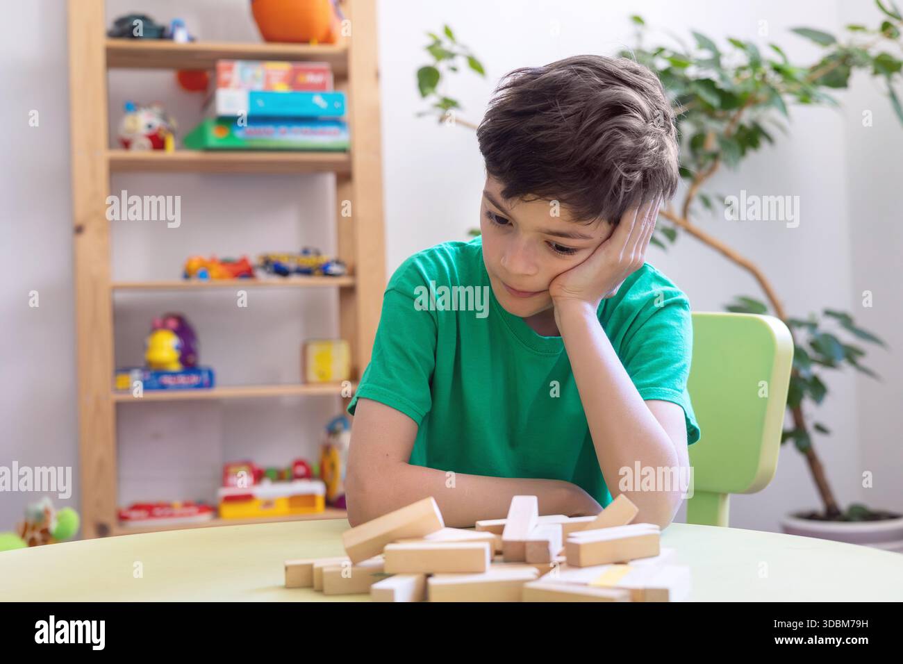 Kind zeigt Frustration während der Lernaktivität mit Holzblöcken. Schwierigkeiten mit der Aufgabenpersistenz bei Kindern mit Autismus oder Dyspraxie. Stockfoto