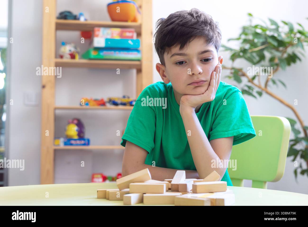 Kind zeigt Frustration während der Lernaktivität mit Holzblöcken. Schwierigkeiten mit der Aufgabenpersistenz bei Kindern mit Autismus oder Dyspraxie. Stockfoto