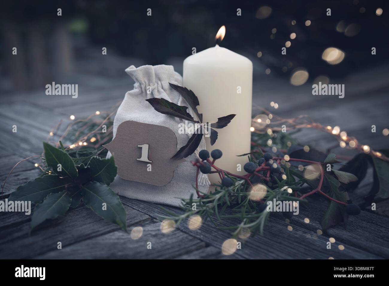 Brennende Adventskerzen mit weihnachtsdekoration und goldenem Bokeh auf einer Terrasse in der Abenddämmerung. Weihnachtshintergrund mit Platz für Text. Stockfoto