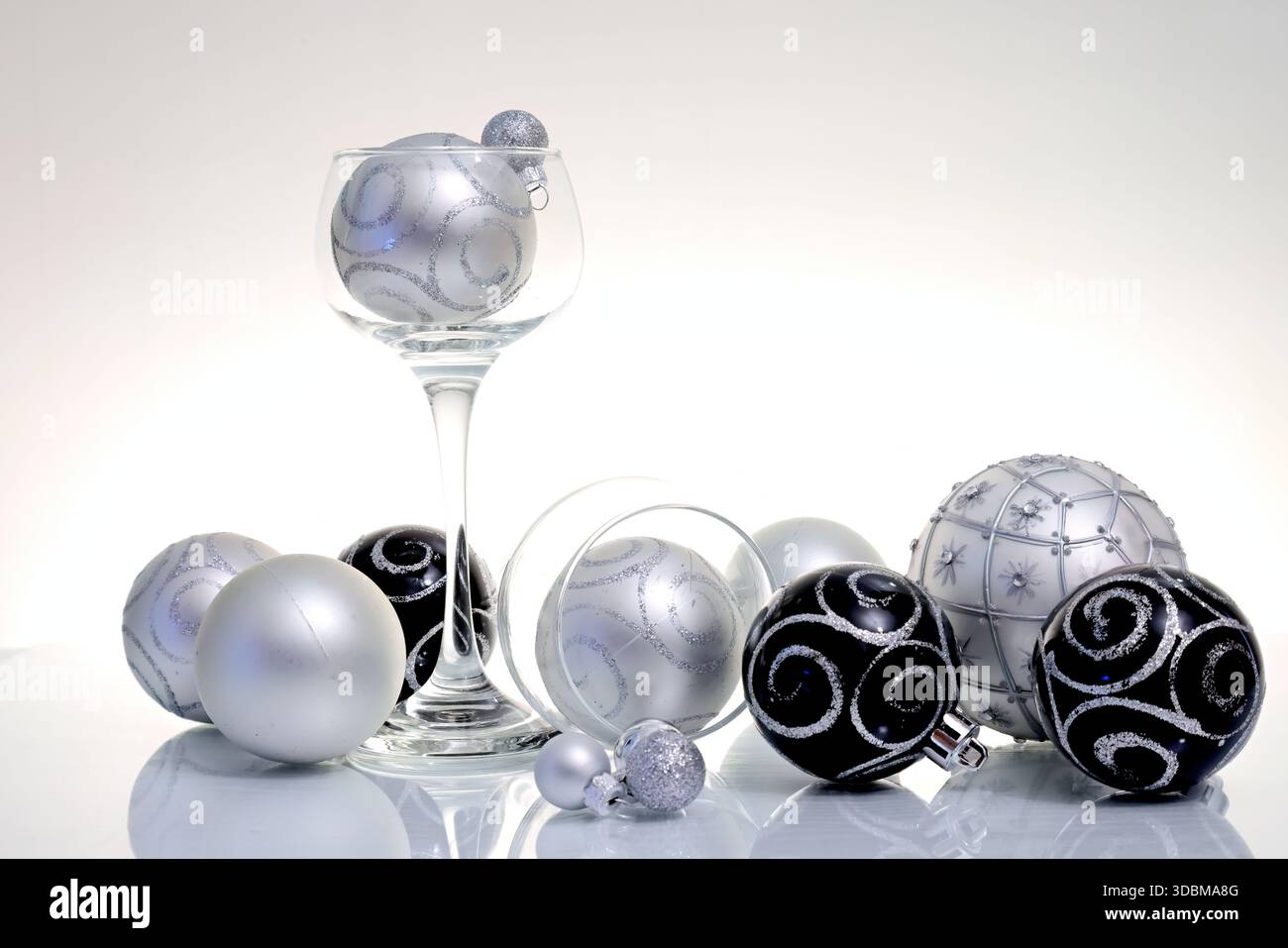 Schwarze und silberfarbene Weihnachtskugeln auf reflektierender Oberfläche Stockfoto