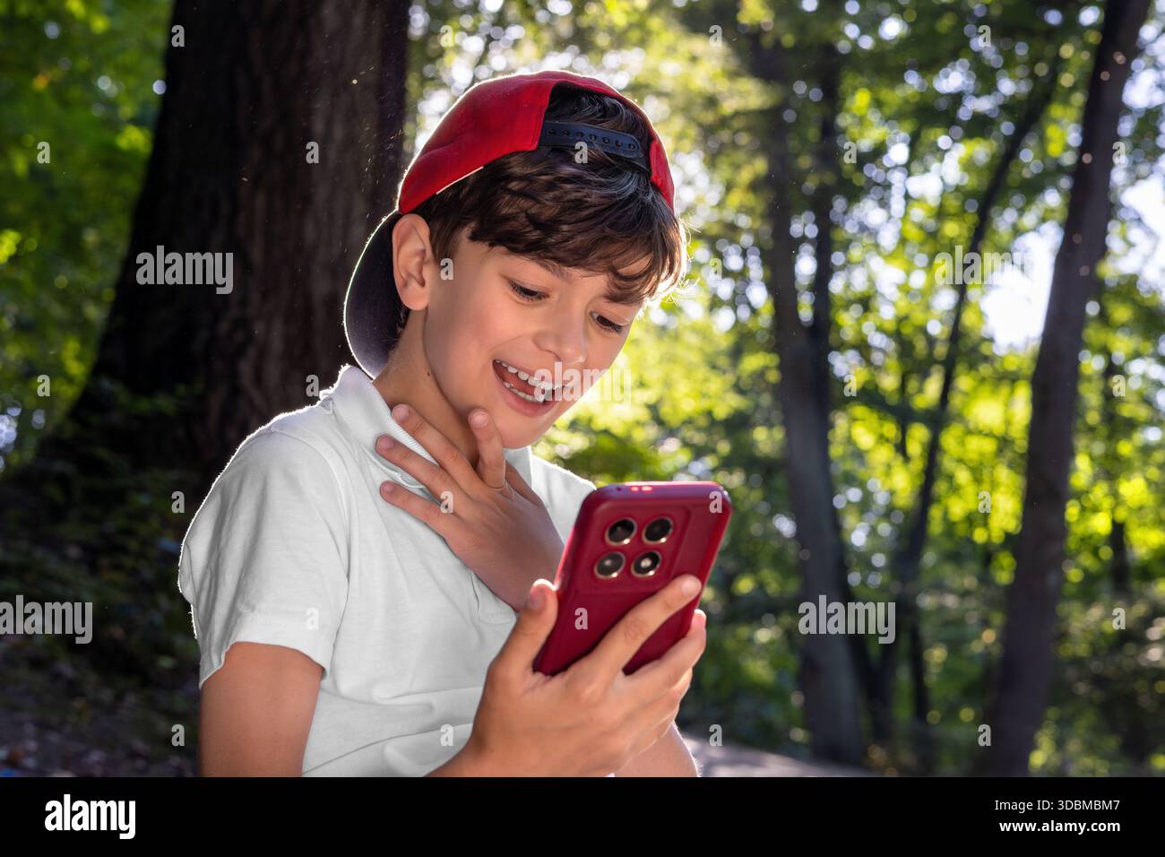 Kind mit Smartphone im Park, Junge mit Mobiltelefon im Freien, digitale Kindheit, Bildschirmzeit, Technologieabhängigkeit, Kinder und Gadgets, soziale Medien, Stockfoto