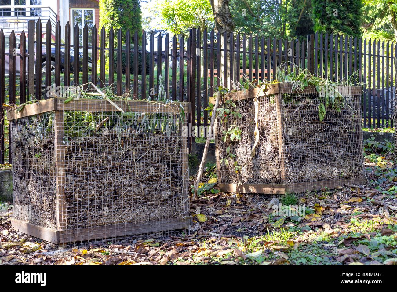 Holzkompostbehälter für den Außenbereich, gefüllt mit organischen Gartenabfällen, die für die nachhaltige Kompostierung pflanzlicher Materialien verwendet werden Stockfoto