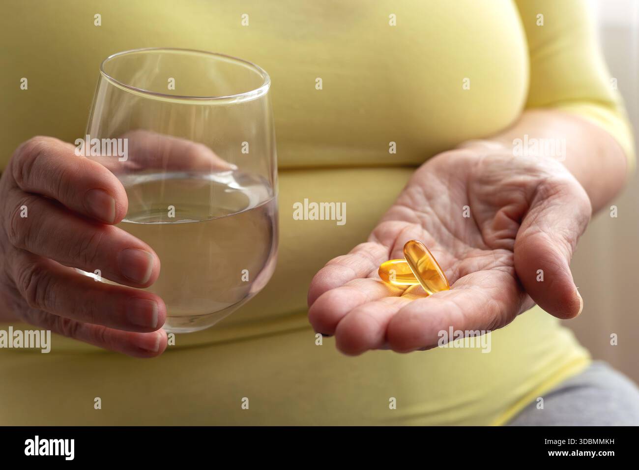 Senior hält Wasserglas und Kapseln in der Hand. Gesundheit im Erwachsenenalter, Erhaltung von Aktivität und Energie. Krankheitsprävention, Vitamineinsatz und Supplem Stockfoto