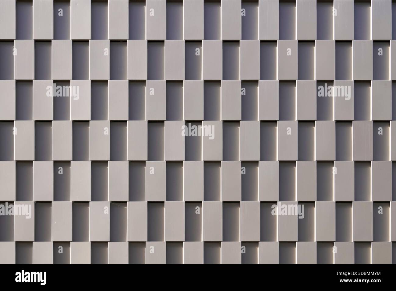 Geometrische Präzision: Funktionelle Eleganz. Dieses Fassadendetail zeigt die strukturierte Gestaltung des Parkplatzes neben der R.evo Neuperlach in München, das von Delugan Meissl Associated Architects entworfen wurde. Das sich wiederholende Gitter aus quadratischen Paneelen verbindet Nutzen mit Ästhetik, während der Rhythmus von Licht und Schatten auf der Oberfläche die funktionale Eleganz verstärkt. Stockfoto