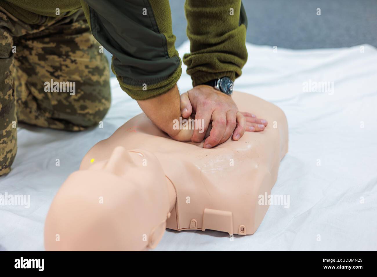 Erste-Hilfe-Training für Soldaten, die HLW-Thoraxkompressionen an einer medizinischen Puppe während des Kurses taktische Medizin durchführen, lebensrettende Fähigkeiten im Notfall, Stockfoto