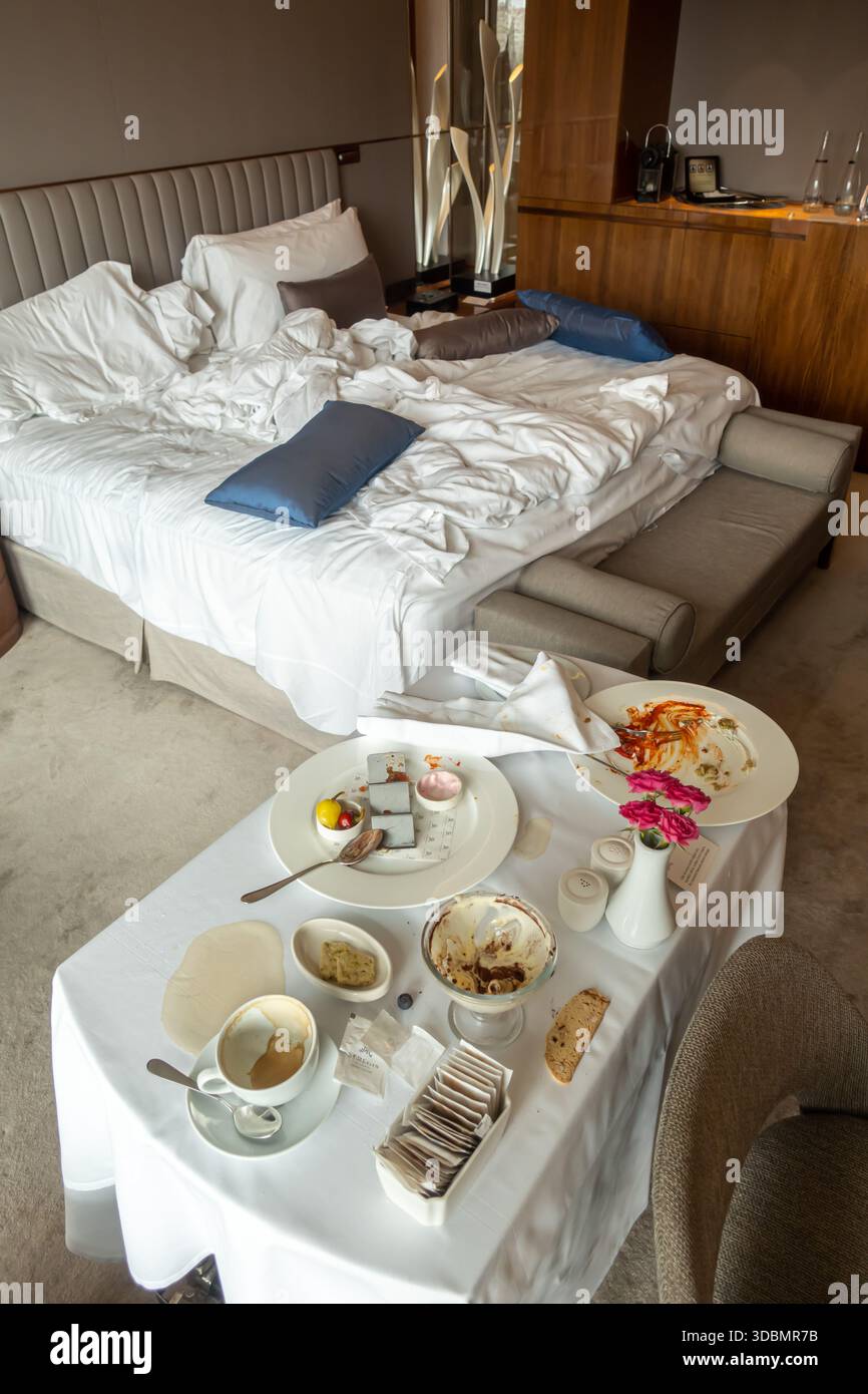Zimmerservice in einem luxuriösen Hotelzimmer, nachdem die Gäste ihre Mahlzeit beendet haben. Besteck und Geschirr, ein Standard für luxuriöses Essen auf dem Zimmer Stockfoto