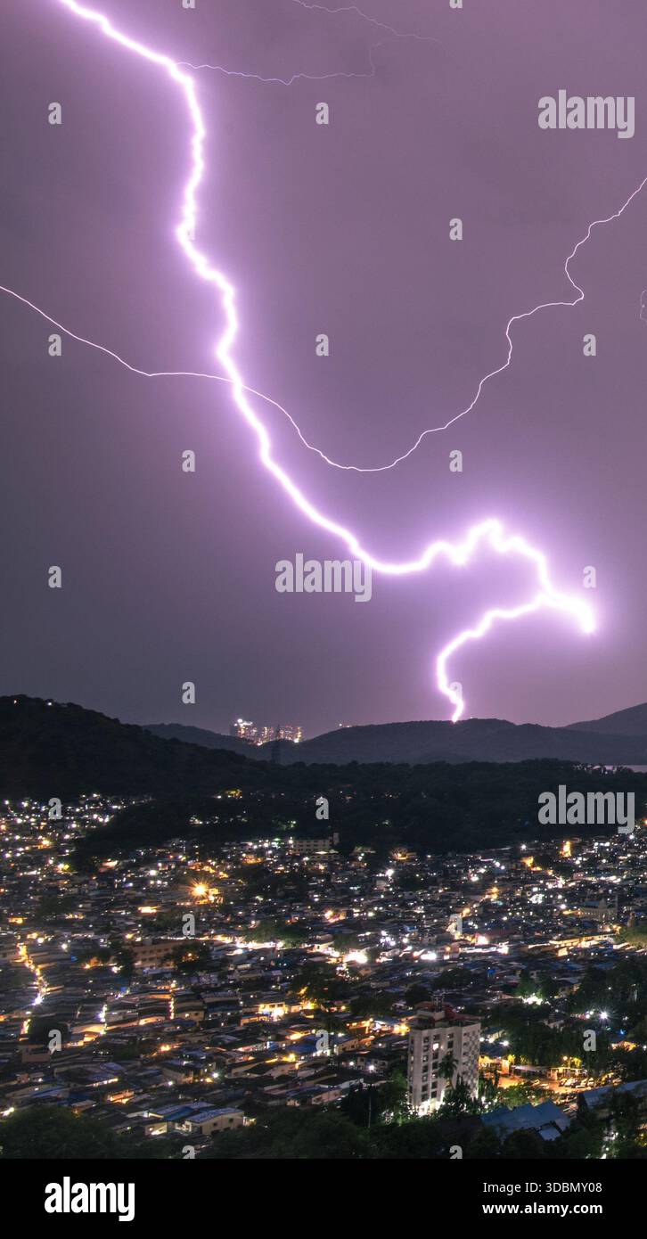 Blick auf eine Stadt, die vom ätherischen Schein eines mächtigen Gewitters erleuchtet wird und lange Schatten über die Landschaft wirft, Mumbai, Maharashtra, Indien. Stockfoto