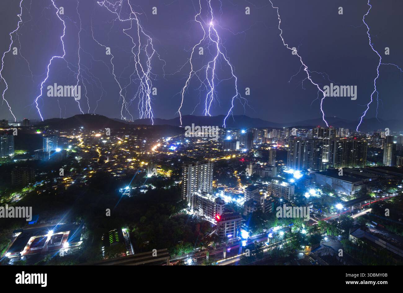 Blick auf elektrisierende Blitze, die den Nachthimmel über der Stadtlandschaft mit hellen Lichtern unter der Stadt beleuchten, Mumbai, Maharashtra, Indien. Stockfoto