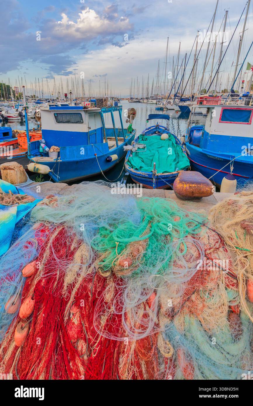 Fischernetze und Boote liegen im kleinen Hafen von La Cala, Palermo, Sizilien, Italien Stockfoto