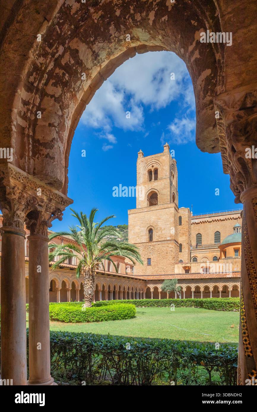 Blick auf den Benediktinerkloster von Monreale, mit kunstvollen Steinbögen, geschnitzten Kapitellen, Säulen, Palmen und dem mittelalterlichen Glockenturm der Kathedrale von Monreale, einem Meisterwerk normannischer Architektur. Metropolstadt Palermo, Sizilien, Italien Stockfoto
