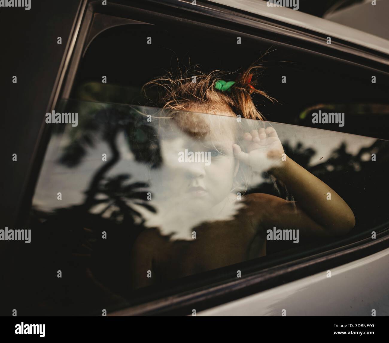 Mädchen schaut aus dem Autofenster und spiegelt Palmen Stockfoto