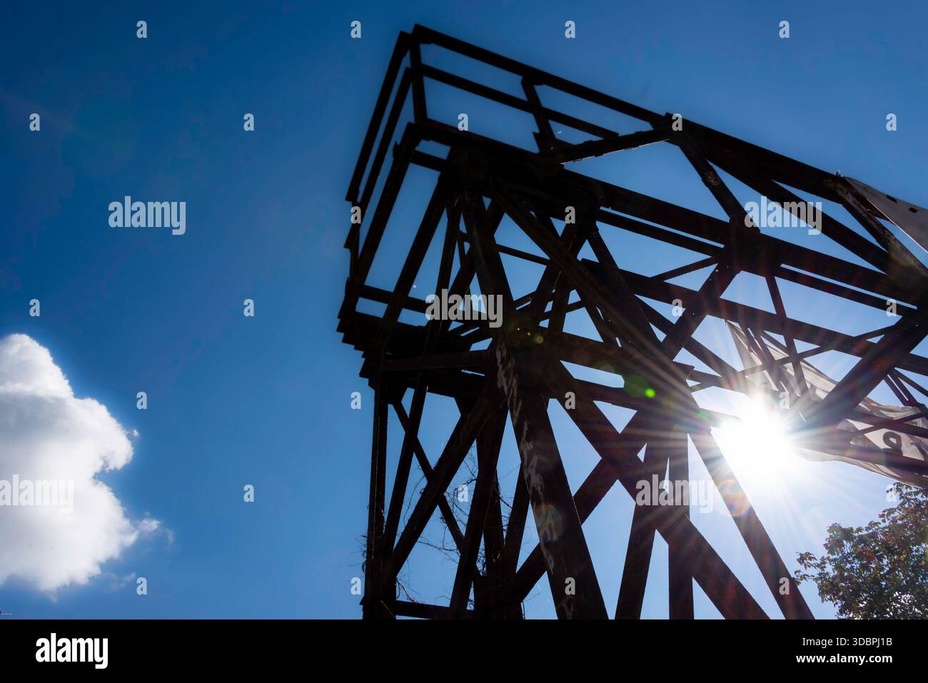 Dramatische flache Silhouette eines Stahlgitterturms vor einem tiefblauen Himmel mit einem hellen Sonnenaufgang. Industrielle Ästhetik bei Görlitzer P Stockfoto