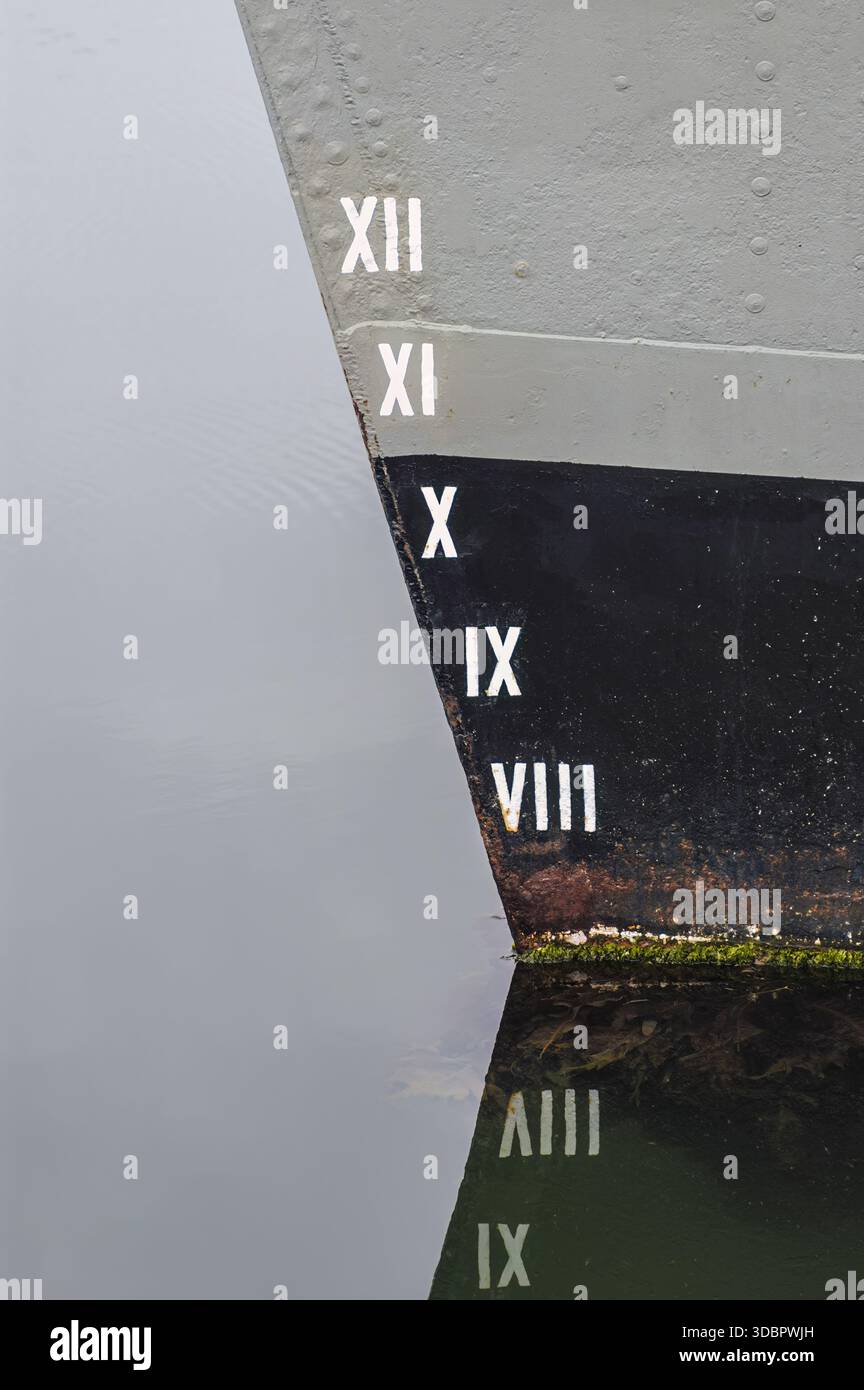 Nahaufnahme eines Schiffsbogens mit römischen Ziffern von VIII bis XII entlang des Rumpfes, reflektiert im ruhigen Wasser Stockfoto