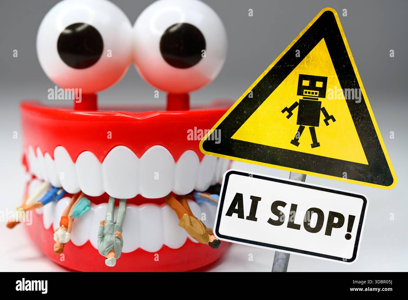 Gefahrenzeichen mit der Inschrift AI Slop vor menschlichen Figuren zwischen den Zähnen der KI, Fotomontage Stockfoto