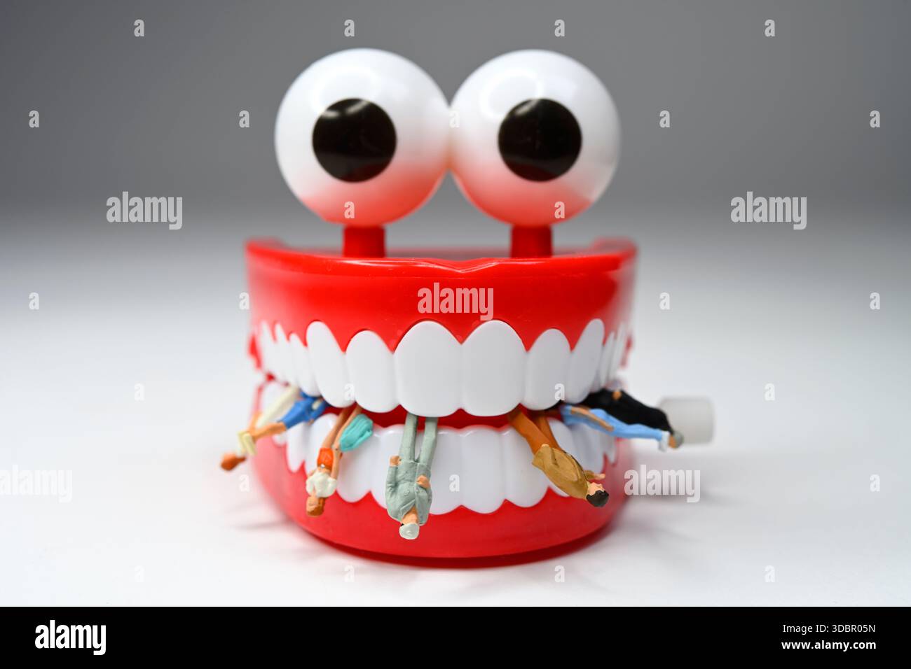 Menschliche Figuren zwischen den Zähnen der KI, symbolisches Foto für die Konkurrenz zwischen KI und Menschen Stockfoto