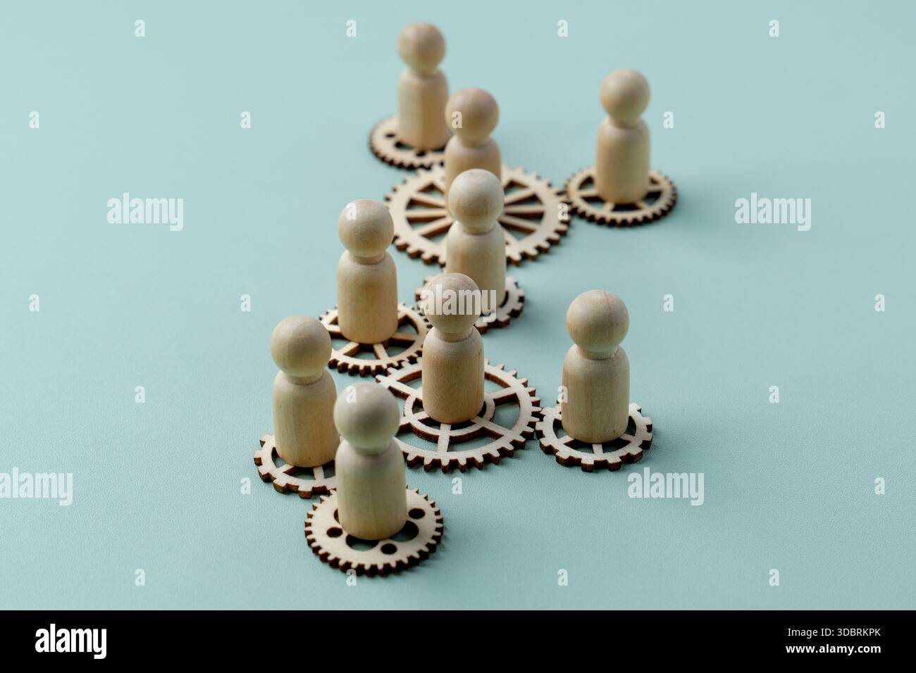 Ein konzeptionelles Bild mit Holzfiguren, die auf miteinander verbundenen Zahnrädern stehen. Teamarbeit, Zusammenarbeit und die Vernetzung des Arbeitskonzepts. Stockfoto