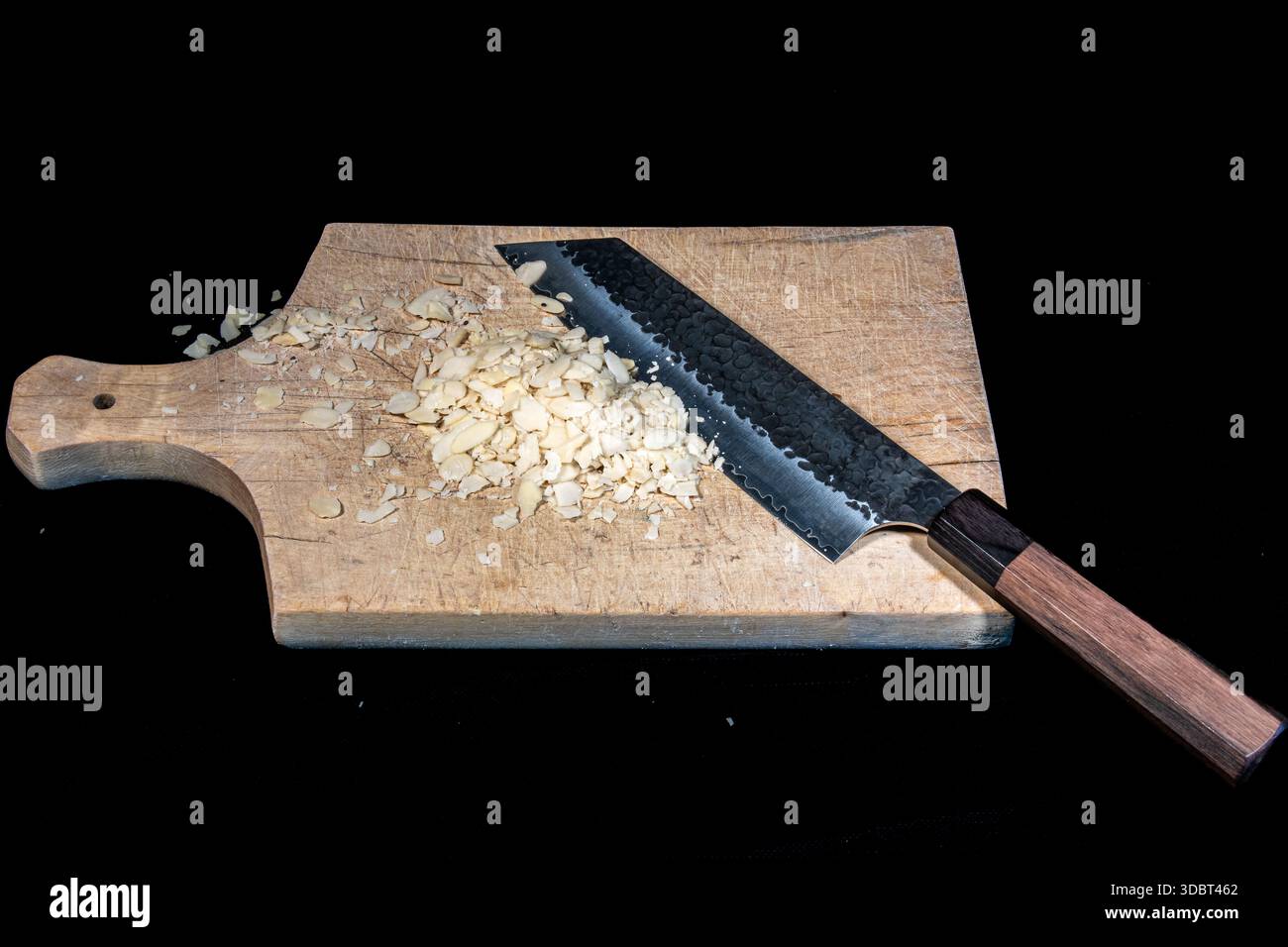 Gehackte Mandeln und Kochmesser auf hölzernem Schneidebrett Stockfoto