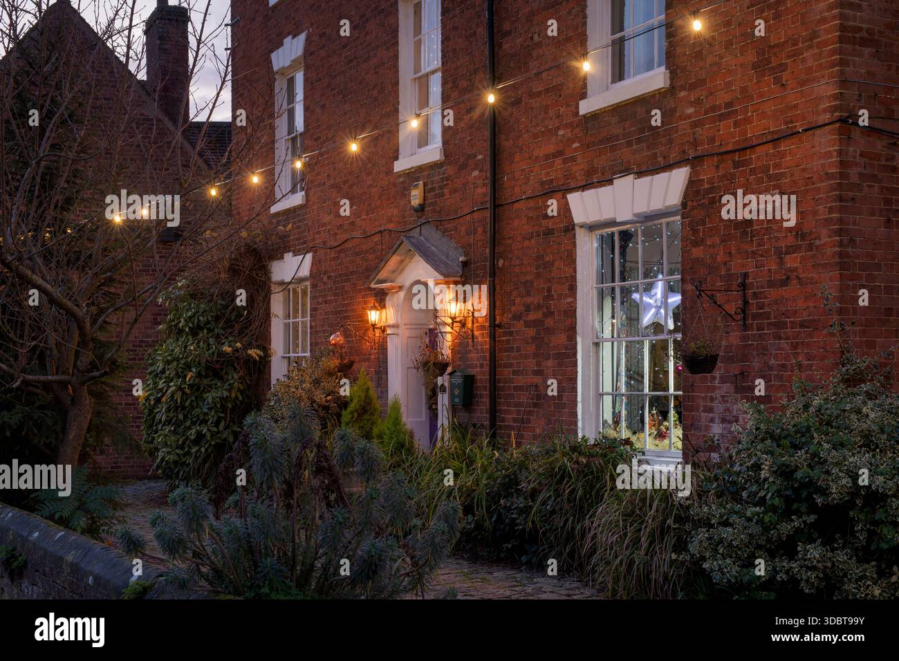 Weihnachtsdekoration im Pfarrhaus entlang der Butterstraße in der Abenddämmerung im dezember. Alcester, Warwickshire, England Stockfoto