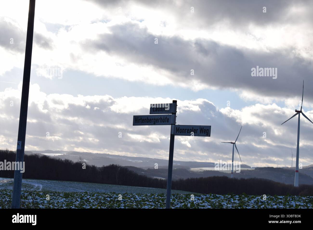 Straßenschilder vor Windkraftwerken Stockfoto