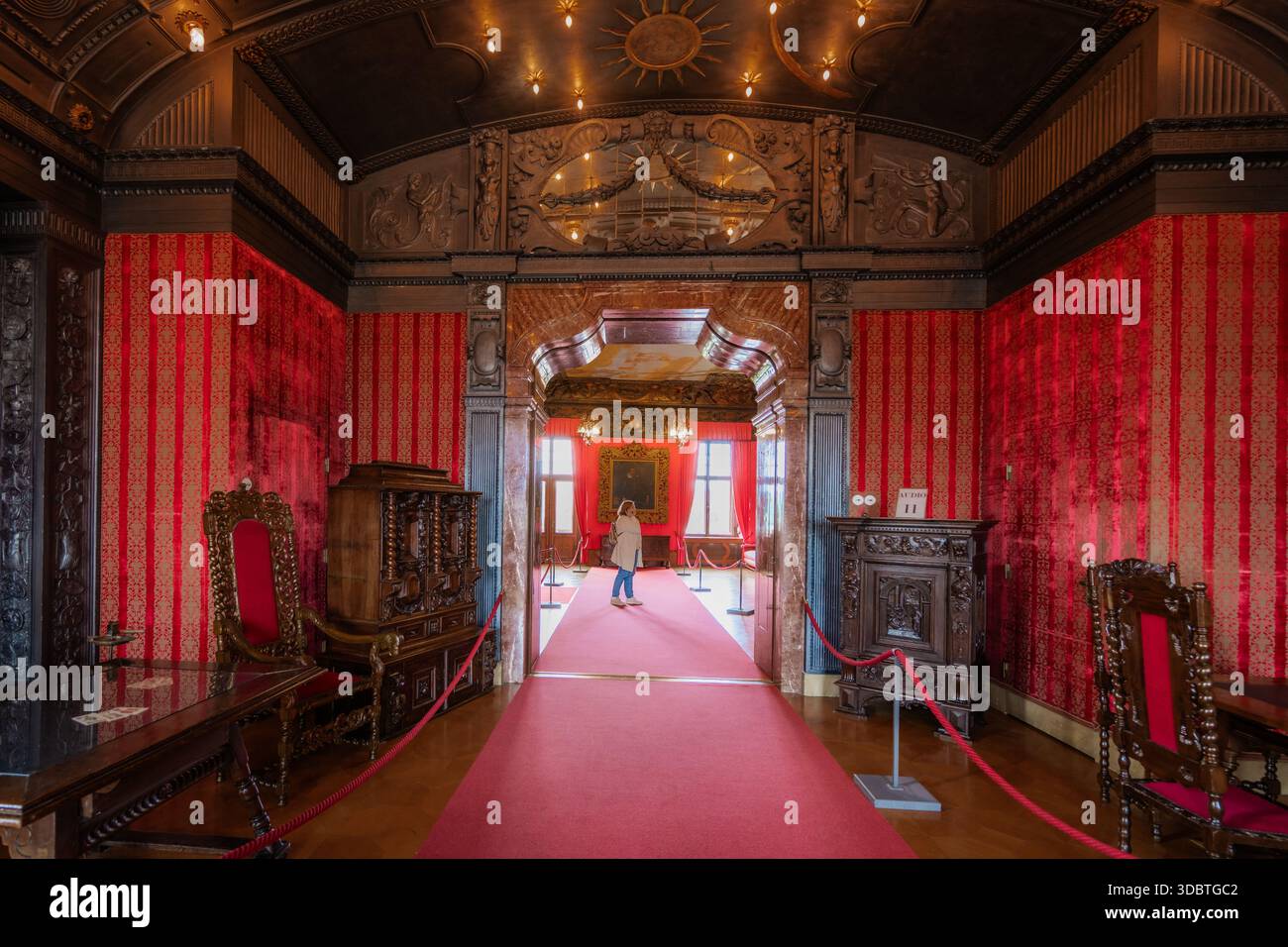 Sigmaringen, Deutschland - 09. September 2025: Blick auf das Innere des Hohenzollernschlosses, wo kunstvolle Schnitzereien auf leuchtend rote Wände treffen und eine Szene schaffen Stockfoto