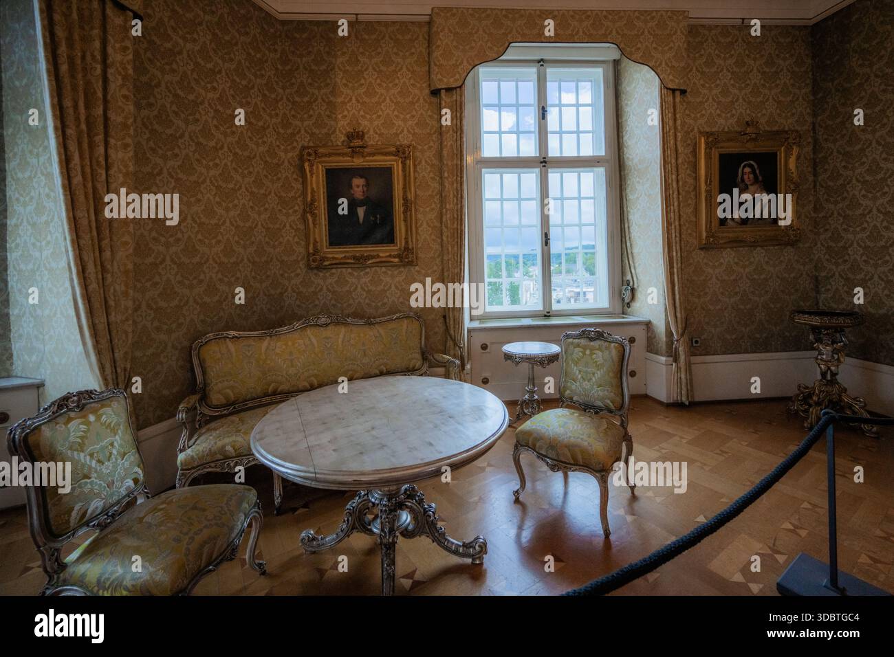 Sigmaringen, Deutschland - 09. September 2025: Blick auf einen Raum im Hohenzollernschloss, in dem kunstvoll verzierte Möbel in sanftem Licht gefiltert sitzen Stockfoto