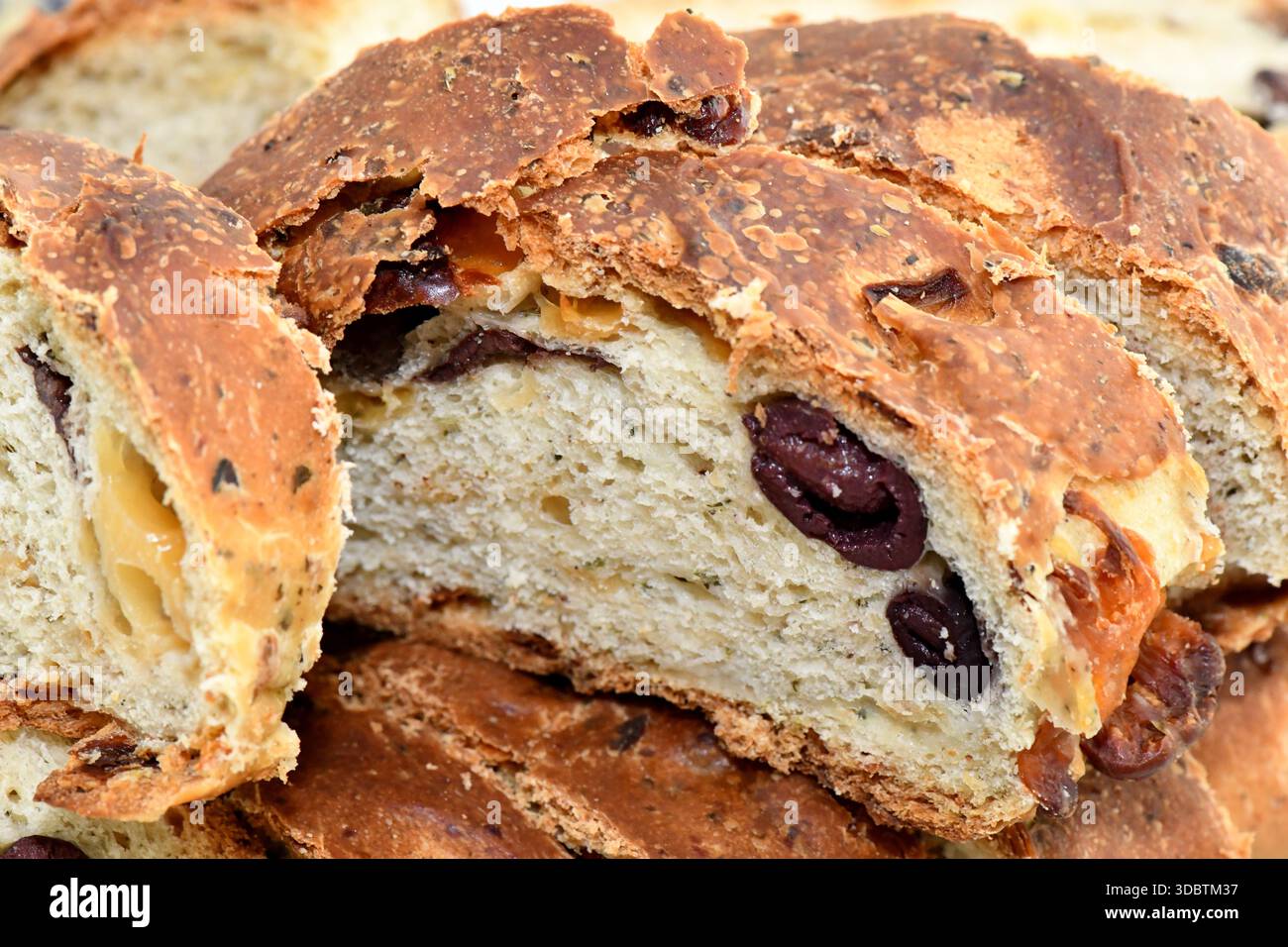 Scheiben traditioneller zyprischer Olivenpitta (Eliopita) mit ganzen schwarzen Oliven und einer goldbraunen Kruste. Stockfoto