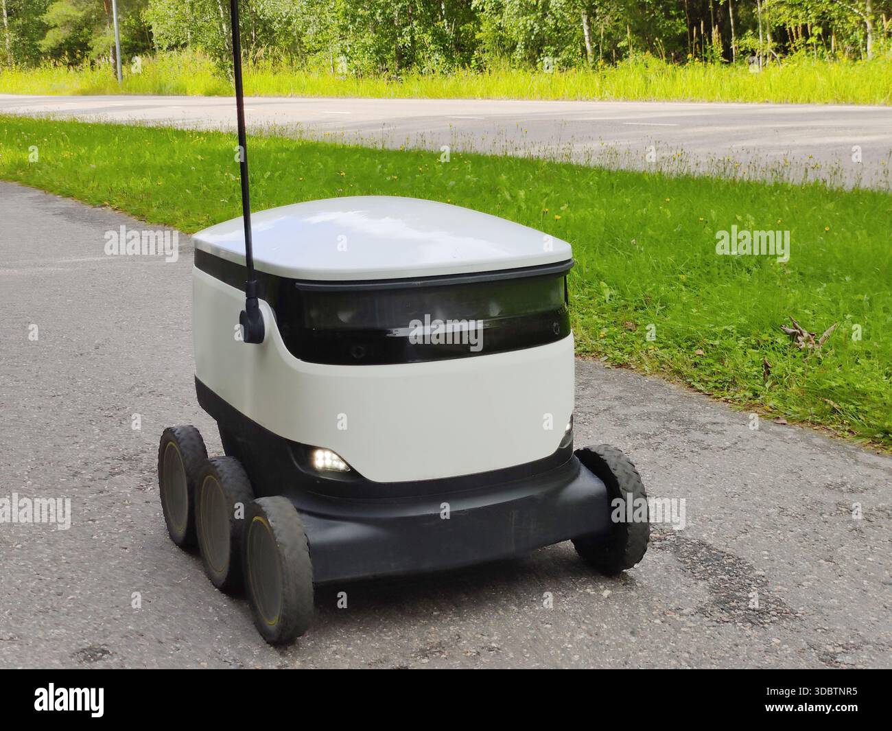 Lieferroboter, der auf einem Bürgersteig in Espoo, Finnland, arbeitet. Sechrädriger, emissionsfreier Roboter, der für die letzte Meile von Lebensmitteln und Lebensmittellieferungen verwendet wird Stockfoto