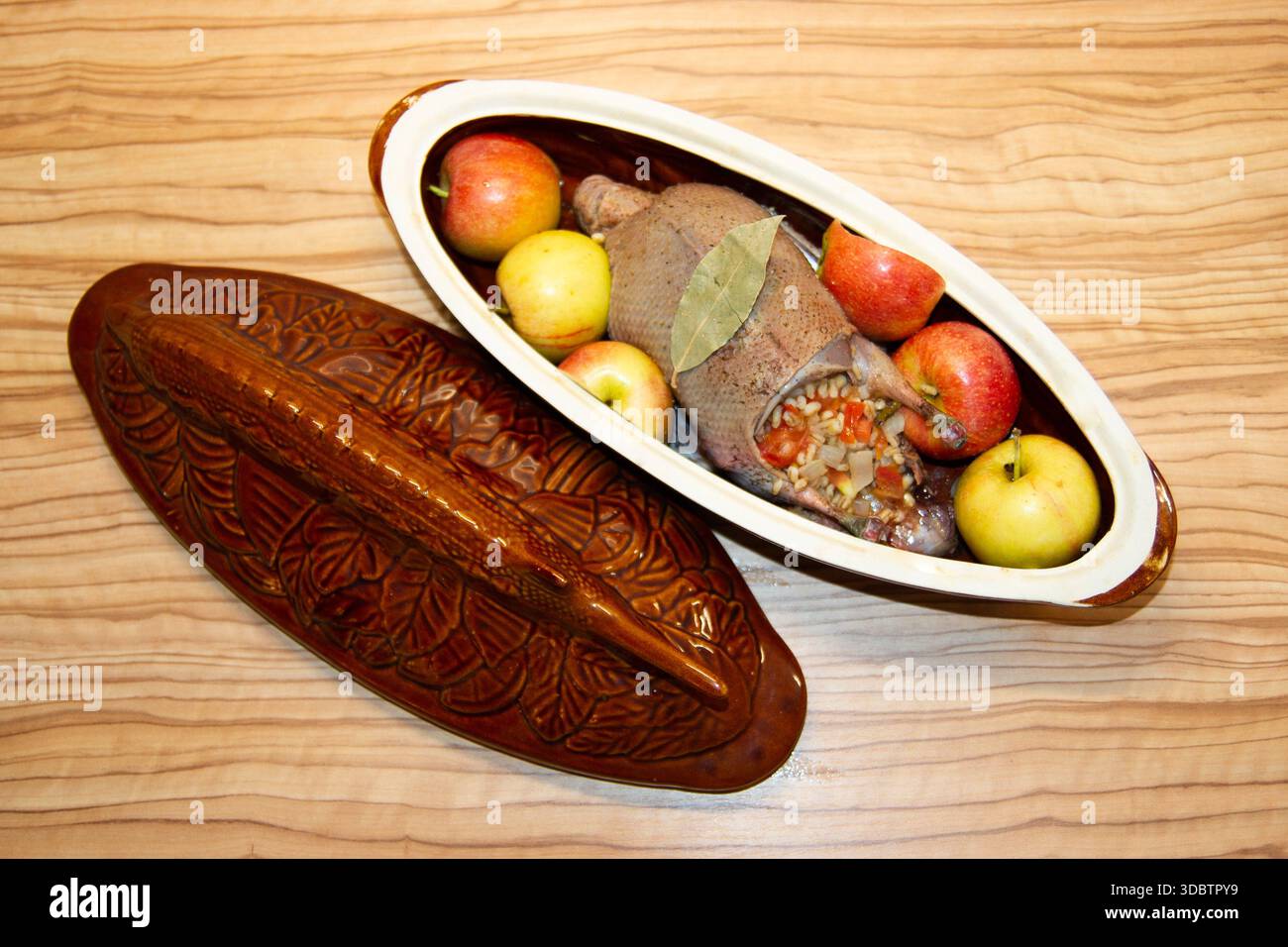 Wildente in Äpfeln in einem Keramikstall mit Lorbeerblatt. Stockfoto