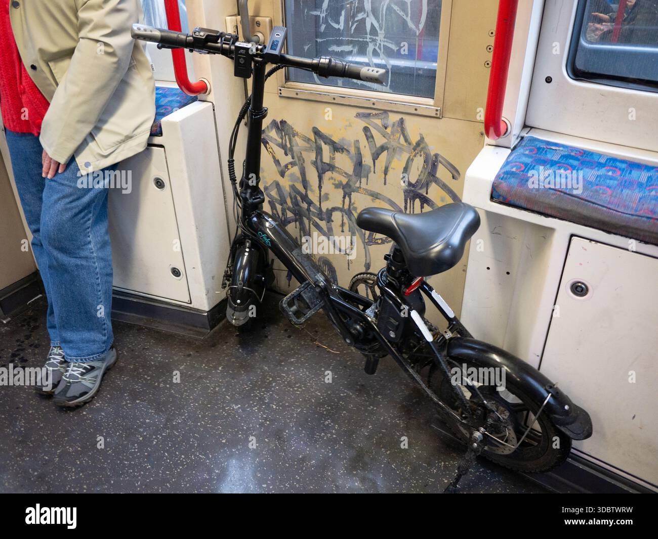 Das Fiido E-Bike wurde in einem mit Graffiti bedeckten U-Bahn-Zug der Central Line in London, Großbritannien, transportiert. Elektrofahrräder sind in der Londoner U-Bahn aufgrund von Brandschutzvorschriften verboten, obwohl dieses Verbot von einigen Pendlern häufig ignoriert wird. Stockfoto
