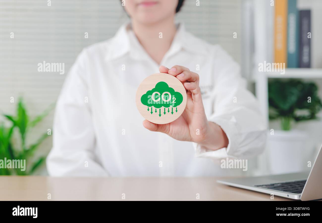 Konzept zur Reduzierung der CO2-Emissionen. Frau mit grünem CO2-Emissionssymbol, das das Bewusstsein für den CO2-Fußabdruck, den Netto-Nullwert und die CO2-Neutralität repräsentiert. Clima Stockfoto