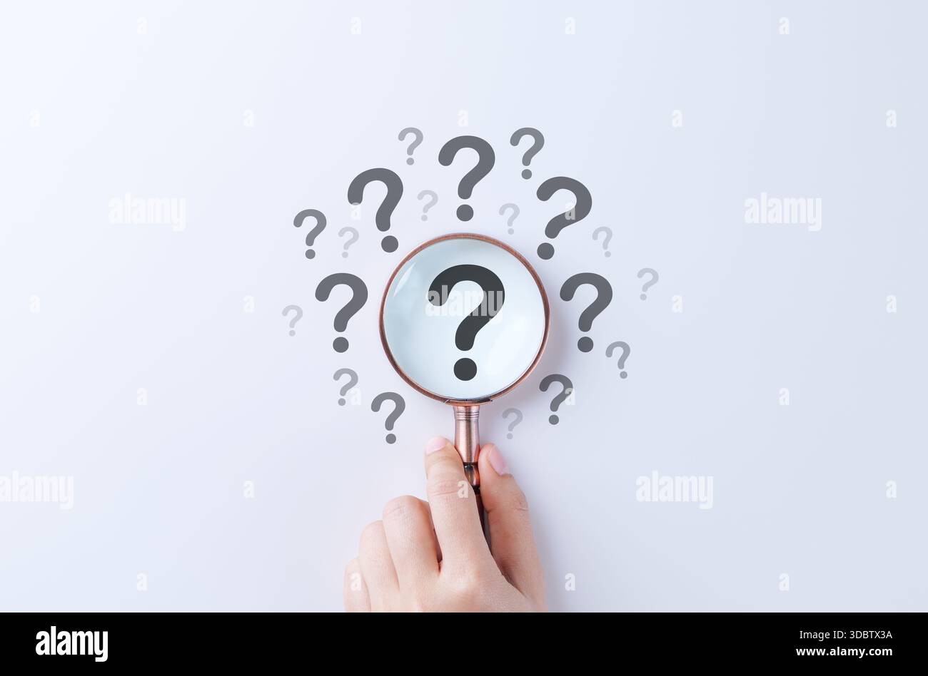 Konzept der Fragezeichen- und Ursachenanalyse. Die Hand hält die Lupe über einem großen Fragezeichen, umgeben von kleineren auf weißem Hintergrund, Stockfoto