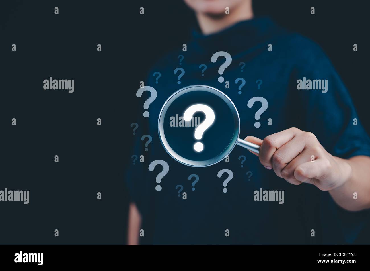 Konzept der Fragezeichen- und Ursachenanalyse. Eine Hand, die eine Lupe über große Fragezeichen hält, die von kleineren umgeben sind, symbolisiert die Ursache Stockfoto