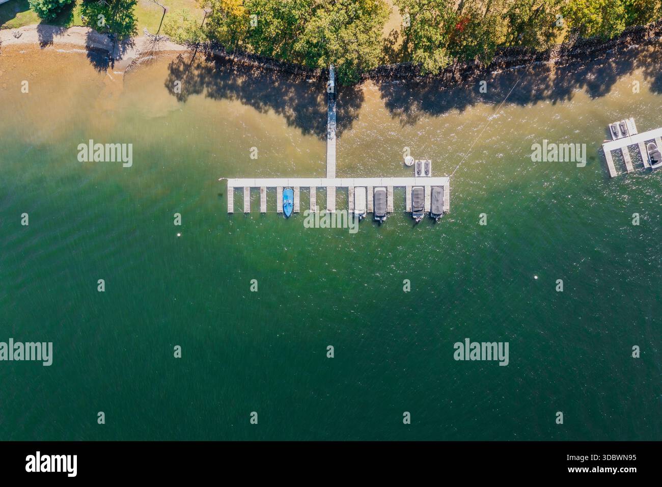 Aus der Vogelperspektive auf das ruhige Wasser des Sees, das auf die bewaldete Küste trifft, wo sich ein Pier in das einladende Wasser des Deep Creek Lake, Deep Dreek, erstreckt. Stockfoto