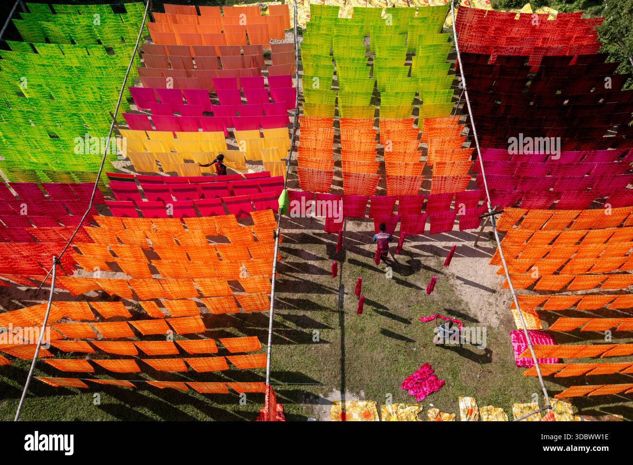 Aus der Vogelperspektive auf leuchtend gefärbte Stoffe, die in der Sonne trocknen und ein atemberaubendes Mosaik aus Farbe und Textur schaffen, Narayanganj, Dhaka Division, Bangladesch. Stockfoto