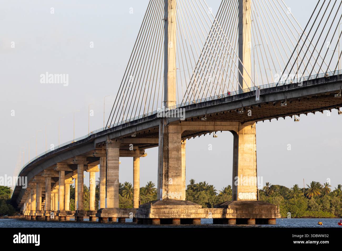 Seilbrücke über den Fluss mit Betonkonstruktion in städtischer Landschaft Stockfoto