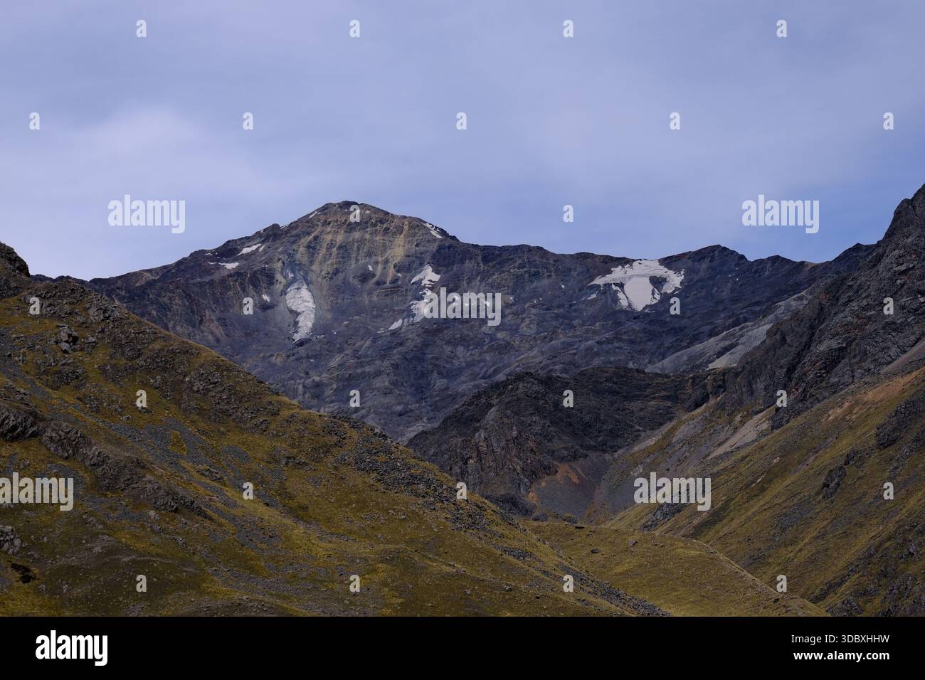 Abgelegenes Andengebirgstal in Peru mit zerklüfteten Gipfeln, felsigen Hängen und Spuren von Schnee unter einem ruhigen Hochlandhimmel. Stockfoto