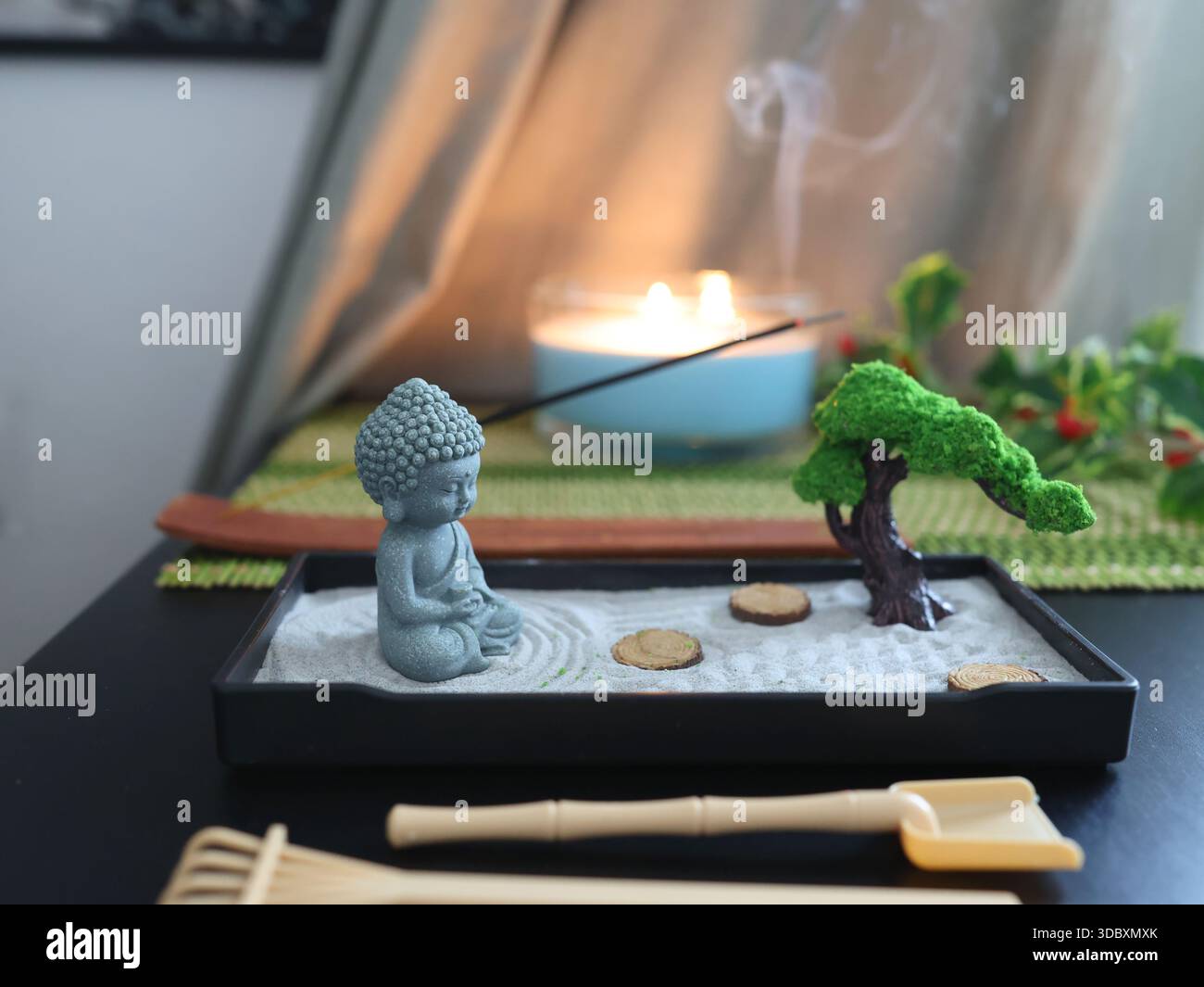 Buddha-Statue im Zen-Stil. Miniatur-Meditations- und Entspannungsset für zu Hause auf dem Tisch mit Räucherstäbchen am Ständer. Östlicher Steingarten. Stockfoto