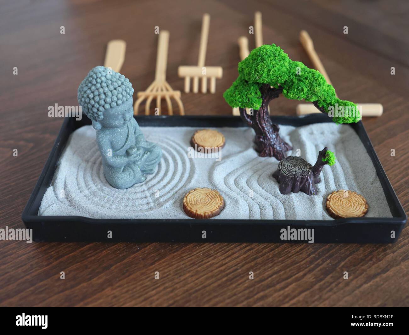 Buddha-Statue im Zen-Stil. Miniatur-Meditations- und Entspannungsset für Zuhause auf dem Tisch. Östlicher Steingarten. Stockfoto