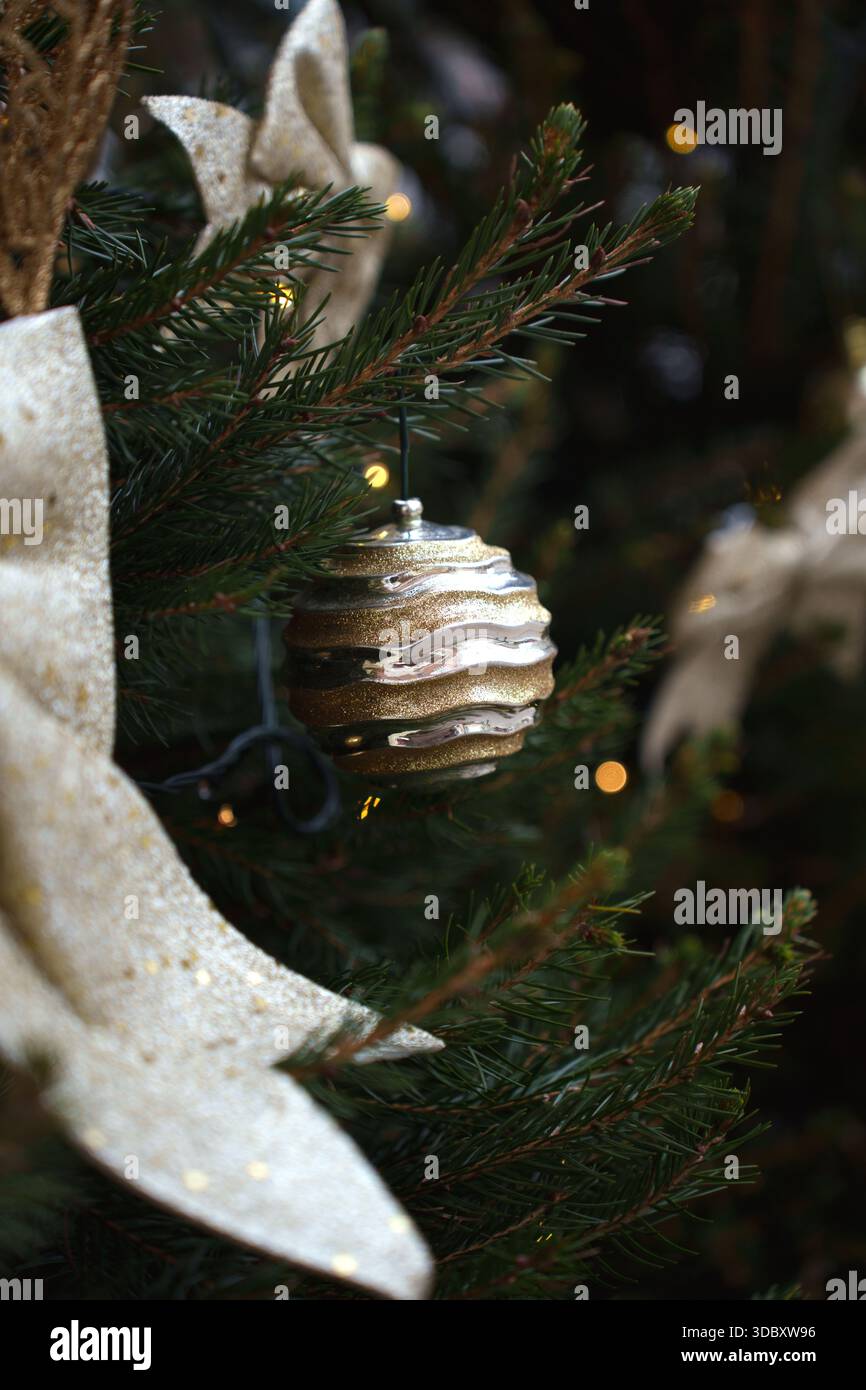 Festlicher weihnachtsbaumzweig mit glitzerndem Ornament und Schleife in warmer Atmosphäre, die Weihnachtsstimmung und Eleganz in sanftem und sattem Glanz einfängt Stockfoto