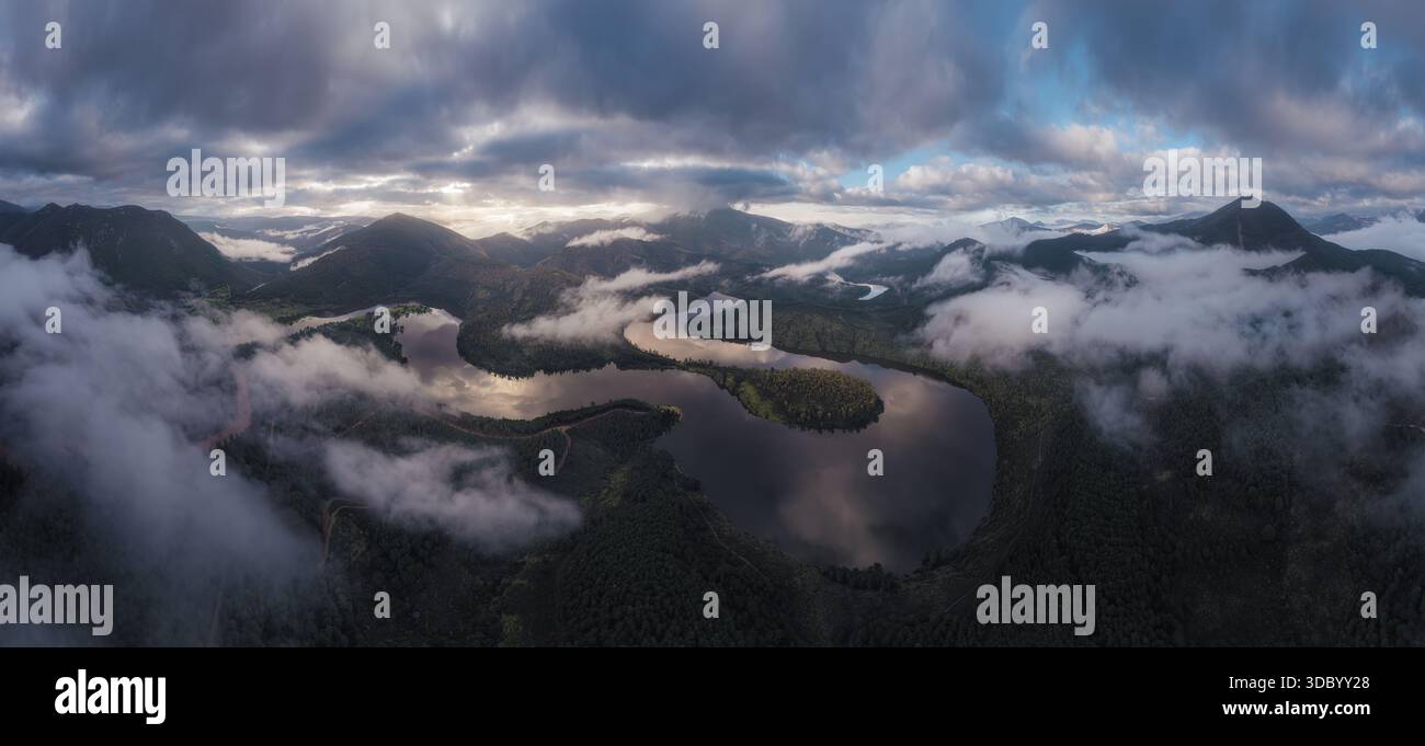 Ein atemberaubendes Panorama eines Flusses, der von sanften Bergen umgeben ist und von schwebenden Nebelschichten bedeckt ist. Der Nebel tanzt über dem W Stockfoto