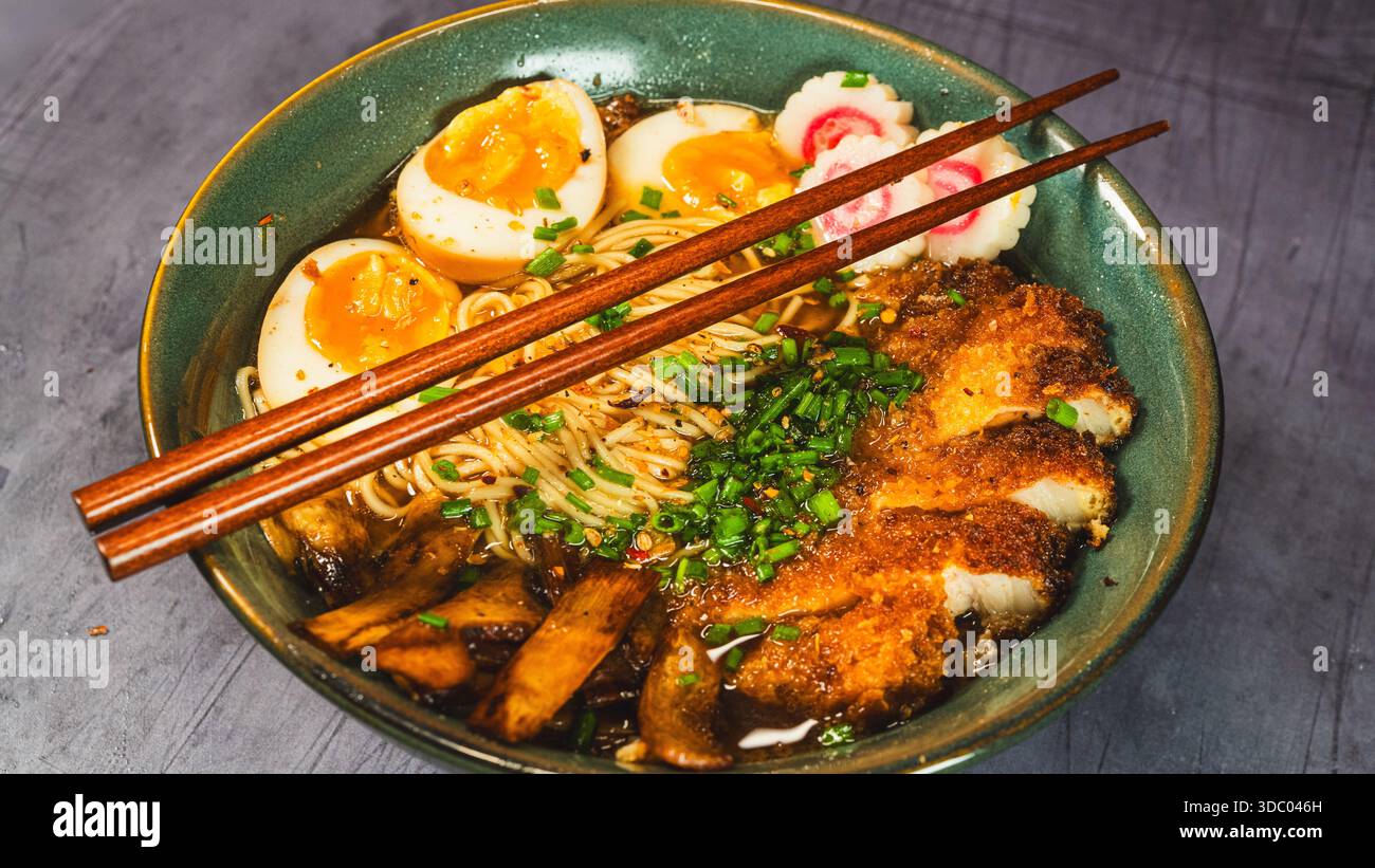 Knuspriges Hühnchen-katsu-Ramen mit weichgekochtem Ei, Bambussprossen und naruto-Fischkuchen. Reichhaltige, herzhafte Brühe. Perfektes japanisches Komfortessen in einer Schüssel. Stockfoto