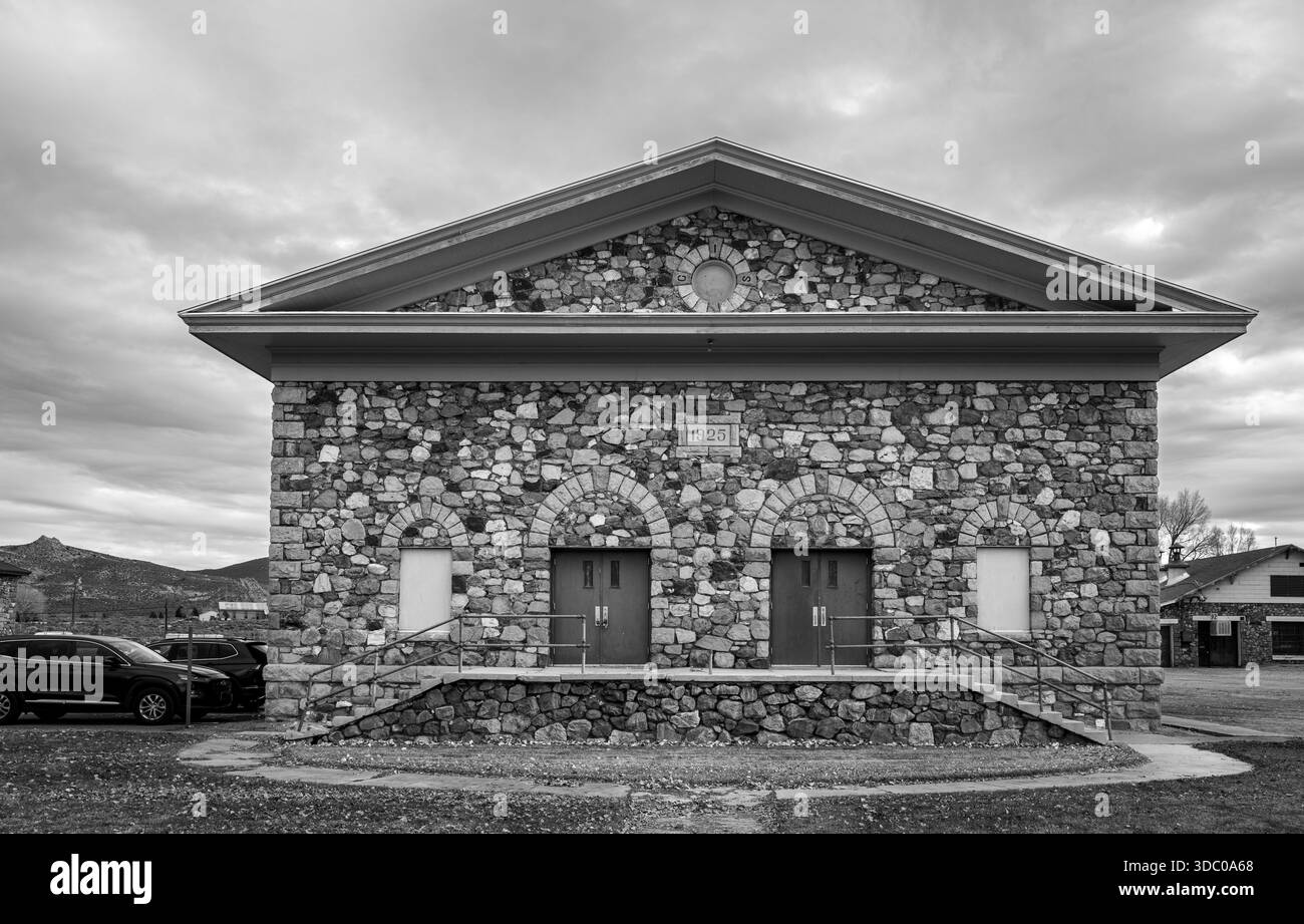 Eine schwarz-weiße Architekturstudie des 1925 in Stein gehaltenen Auditoriums an der Stewart Indian School mit einheimischem Stein unter bewölktem Himmel. Stockfoto