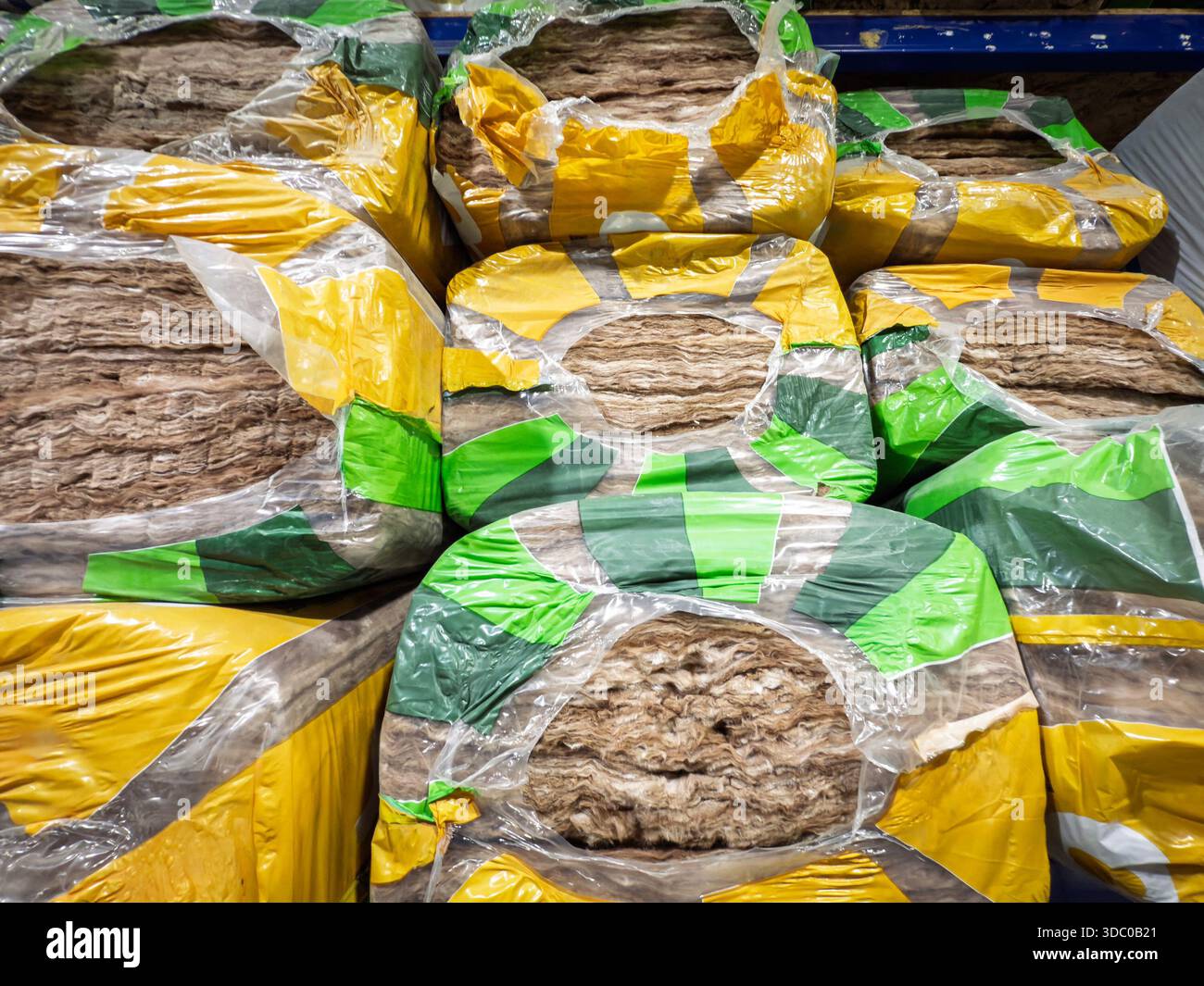 Stapel von Isolierschläuchen aus Mineralwolle, die in Kunststoffmarkenplatten auf den Regalen des Lagers gewickelt sind. Das Fasermaterial für thermische und akustische Leistung Stockfoto