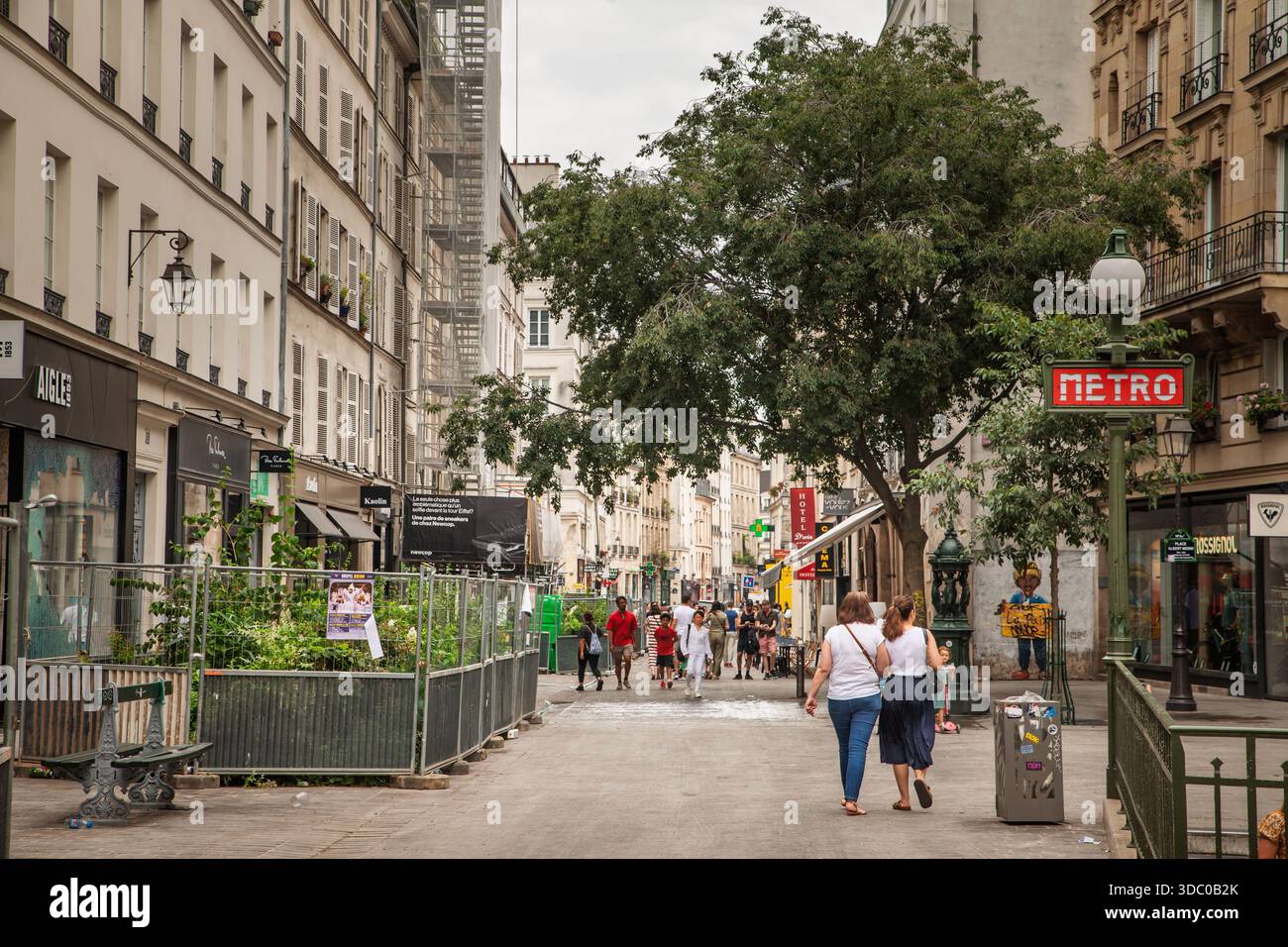 PARIS, FRANKREICH - 22. JUNI 2025: Blick auf die Rue du Temple im Marais, Paris, mit Fußgängern, Geschäften und klassischen Fassaden mit einem alten Metro-Schild Stockfoto